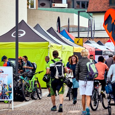 Zeltreihe von 4x4 Faltzelten in Schwarz und Limone mit Ergon-Logo an den Seitenwänden beim Brixen Bike Festival